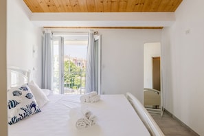 A hotel room with a bed, a window with curtains, a view of buildings outside, and a mirror on the wall. - Seaside Apartment in Porto Potenza Picena (Potenza Picena)