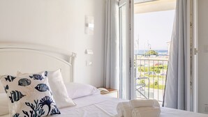 Hotellihuone, jossa on sänky, merinäköala ja parveke, jossa on kaide.