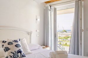 A hotel room with a bed, a view of the sea, and a balcony with a railing. - Seaside Apartment in Porto Potenza Picena (Potenza Picena)