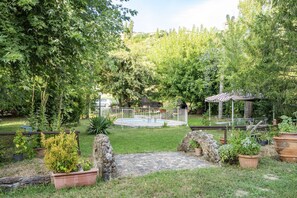 A backyard with a stone pathway, a small pool, a gazebo, and various potted plants. - Podere Vallino - Suite Lavanda (Castelfiorentino)