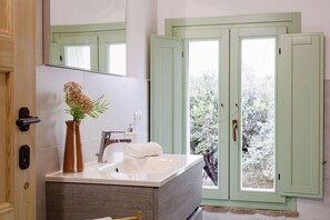 A bathroom with a sink, mirror, and a window with a view of trees. - Villa Zena in Cingoli (Cupramontana)