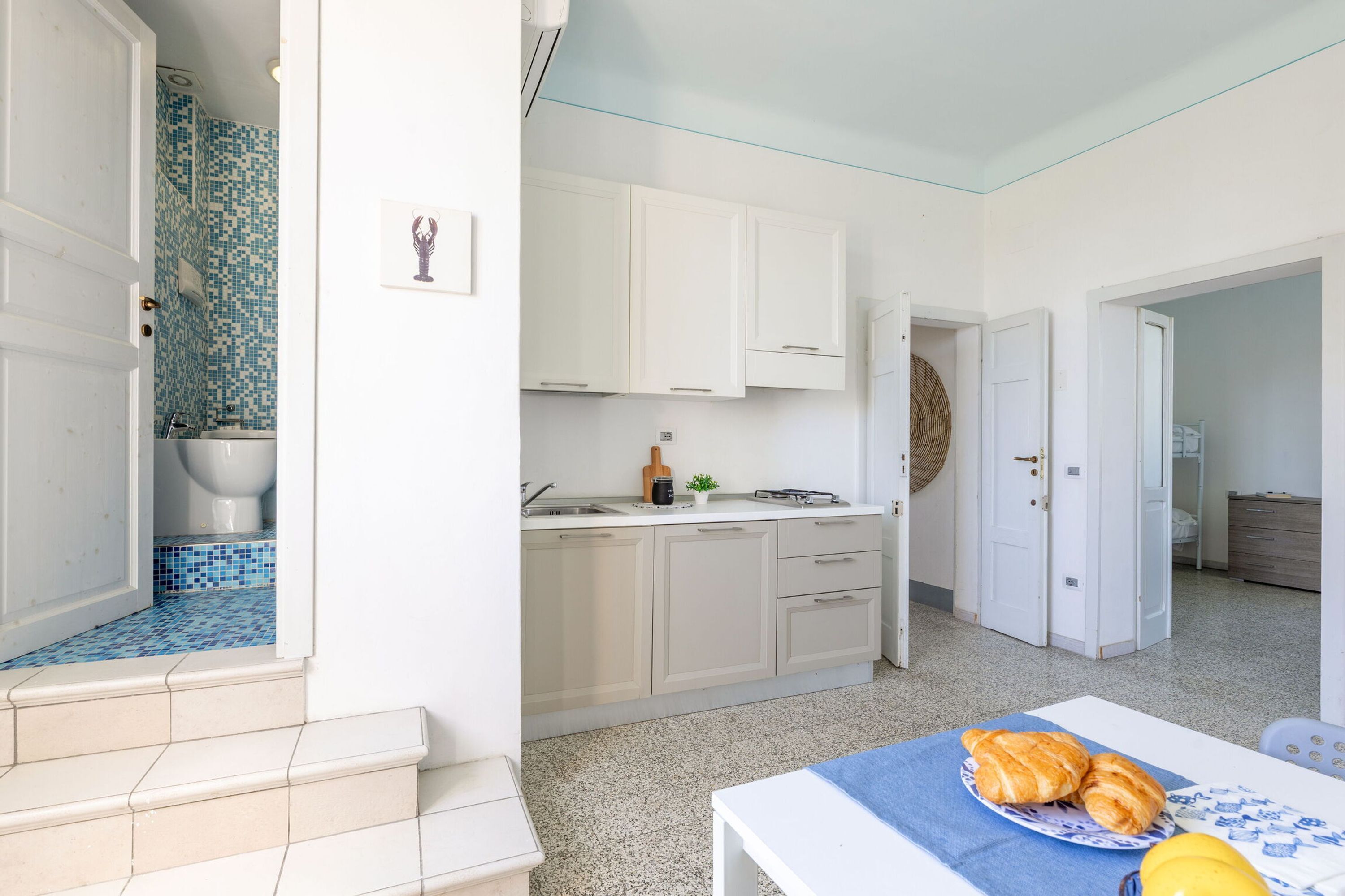 A kitchen with white cabinets, a sink, and a dining area with a table set for two.
