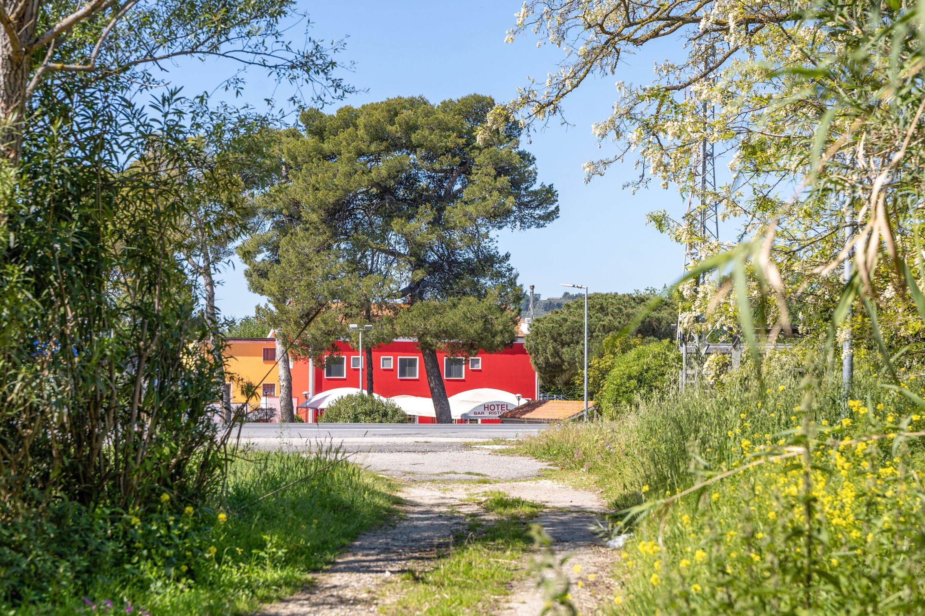 A pathway leading to a red building with a sign indicating it is a hotel and bar.