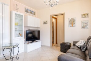 Ein Wohnzimmer mit Flachbildfernseher, Glastisch, Sofa und Kunstwerken an den Wänden.