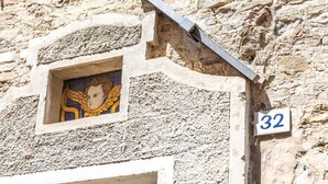 A building with a stone facade, a window with a painted figure, and a number sign '32'. - Suite Sinfonia Oro in Bevagna (Bevagna)