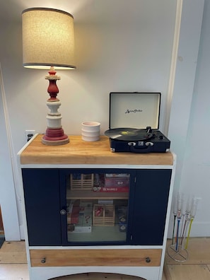 Ein Holzschrank mit Plattenspieler, Lampe und Scrabble-Spiel.