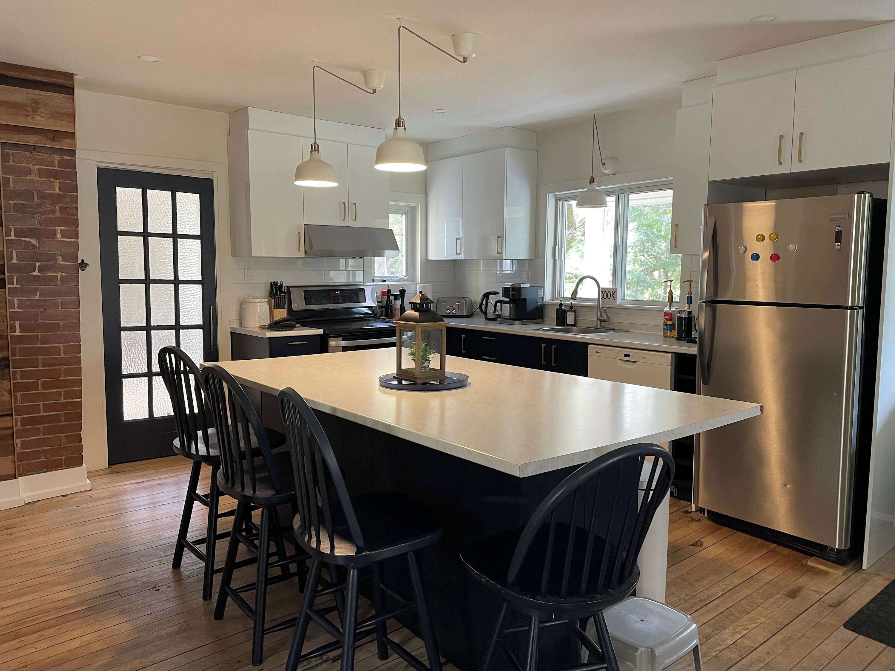 A modern kitchen with a central island, stainless steel appliances, and pendant lighting.