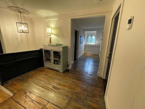 A hallway with wooden flooring, a bench, a cabinet with drawers, and a lamp. - L'Ancestrale de Fitch Bay (Magog)