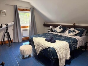 A bedroom with a telescope, a fluffy white stool, and a bed with patterned bedding. - L'Ancestrale de Fitch Bay (Magog)
