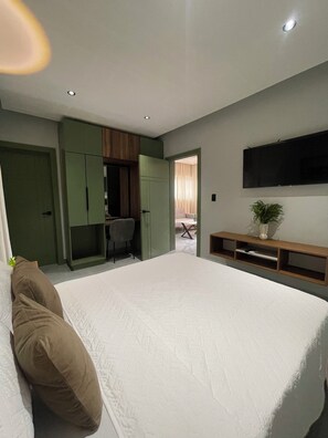 Un dormitorio con una cama grande, un escritorio y un televisor.
