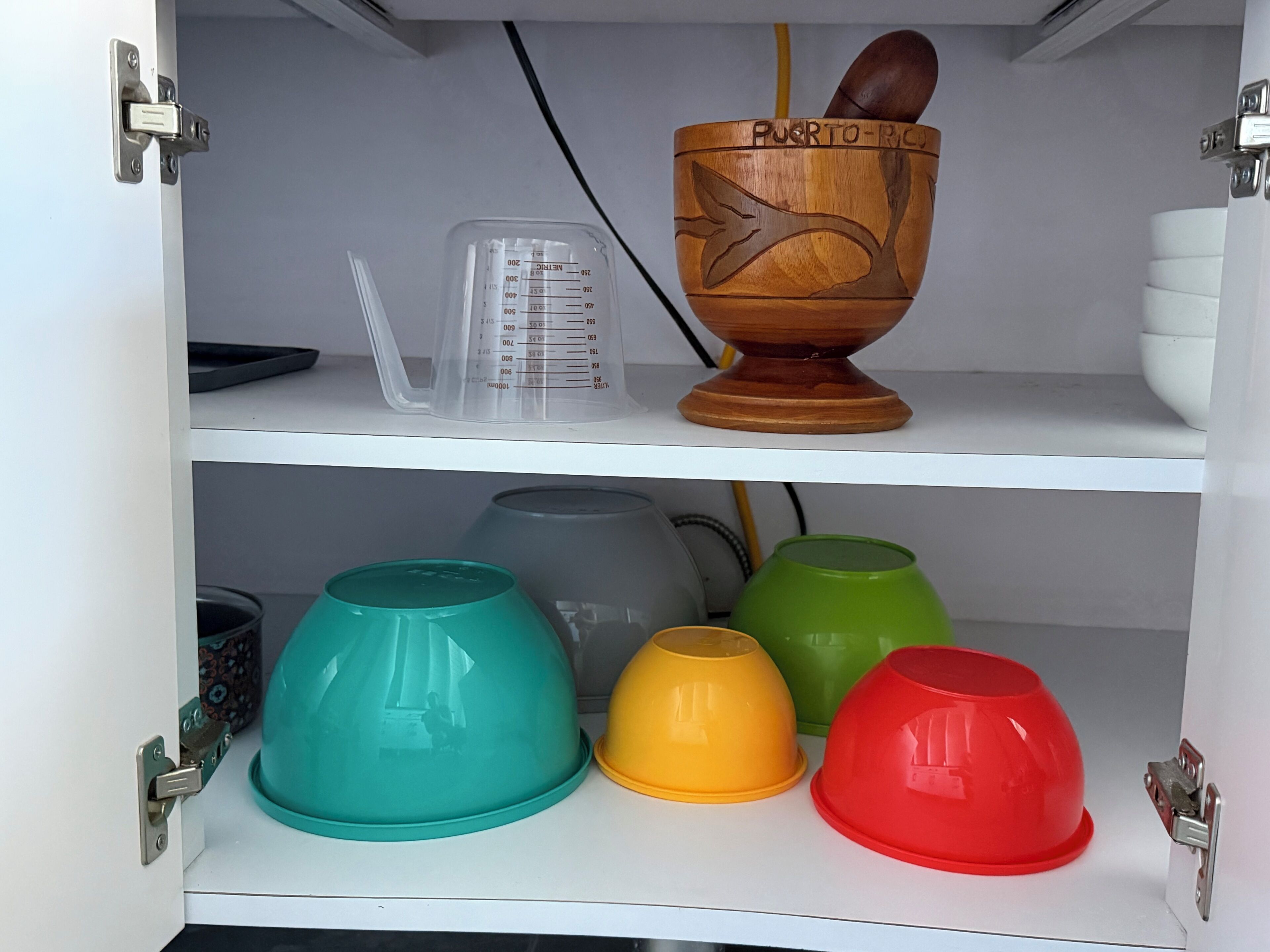 Een keukenkastje met een houten kom met de tekst 'PUERTO RICO' en maatbekers.