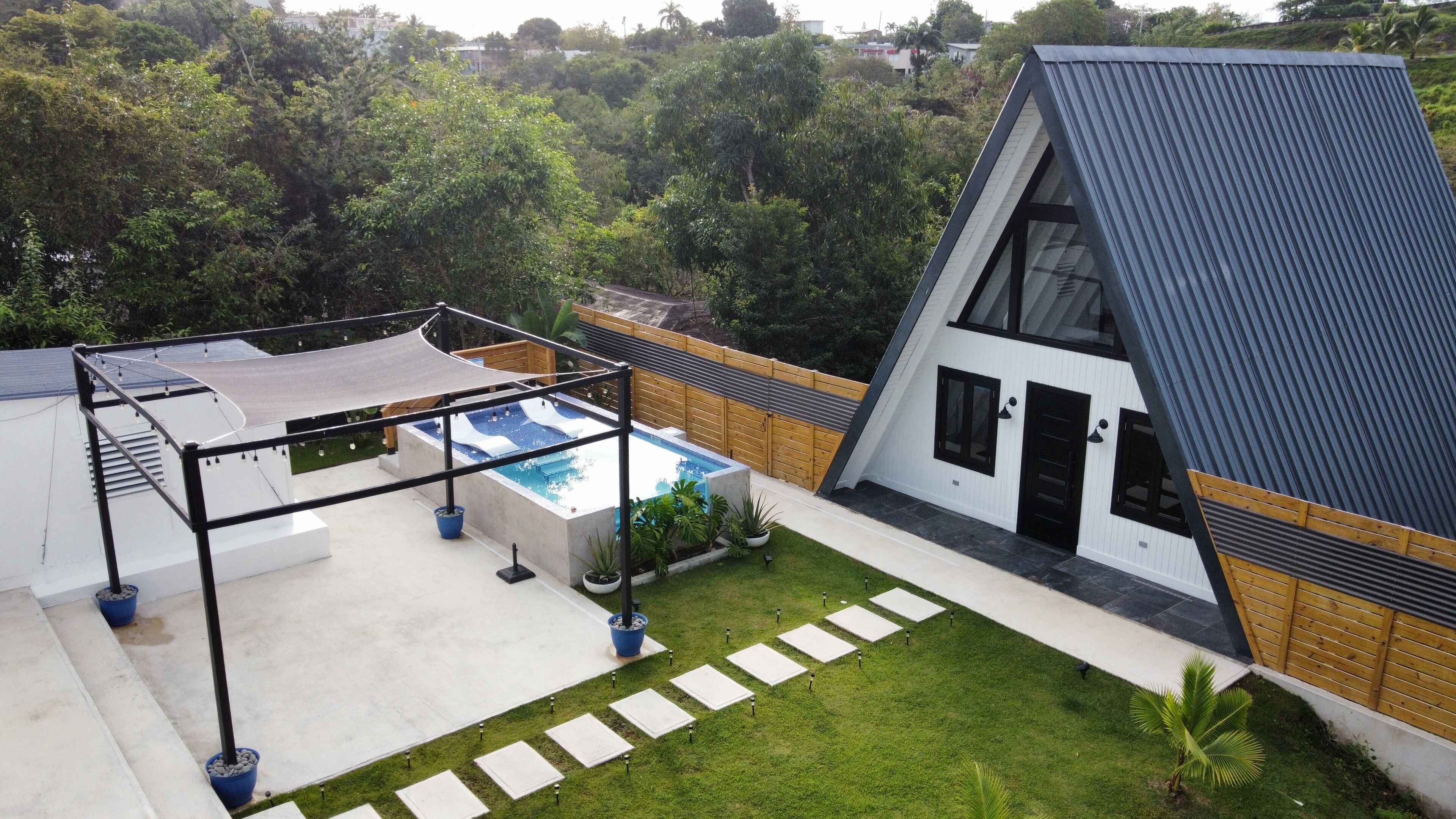 A modern house with a swimming pool, a covered patio, and a well-maintained lawn.