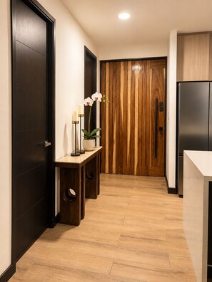 A hallway with a wooden door, a bench with candles, and a refrigerator. - Las Ramblas 3 Bedroom Penthouse (Santa Tecla)