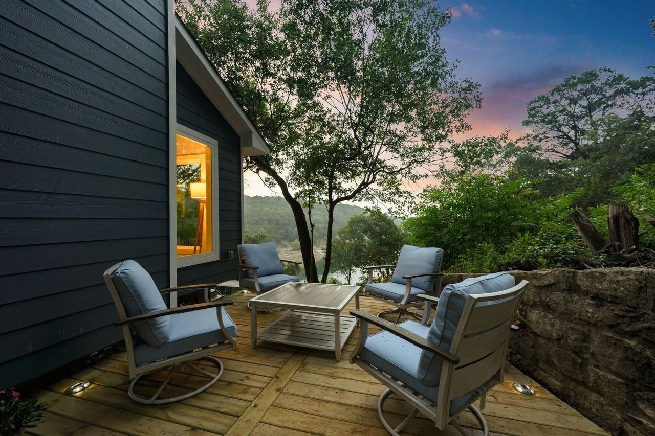 An outdoor deck with a table and chairs, overlooking a natural landscape.