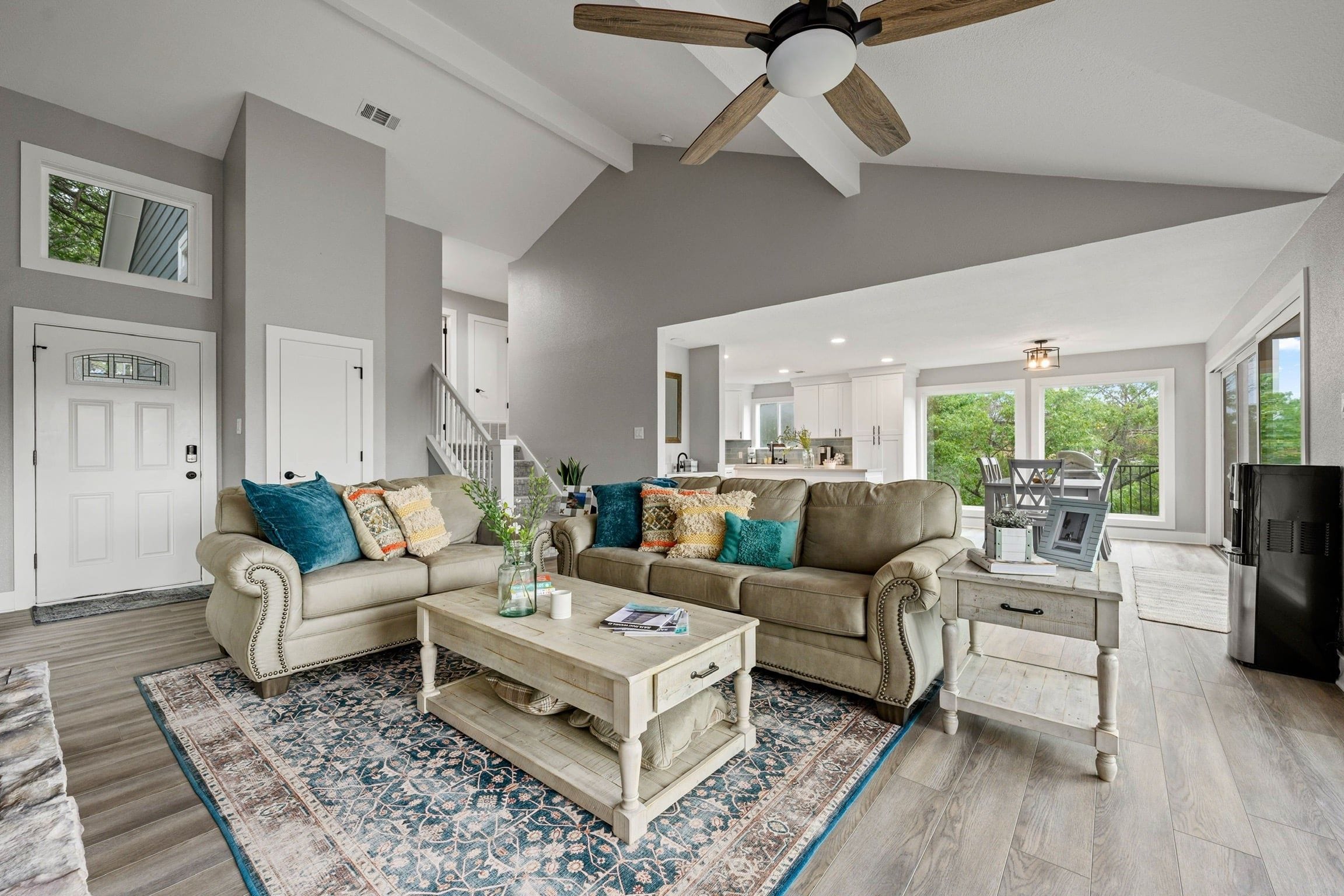 A spacious living room with a high ceiling, a ceiling fan, and a large window providing natural light.