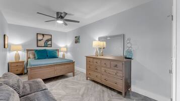 Un dormitorio con una cama, un aparador, un ventilador de techo y una mesita de noche.