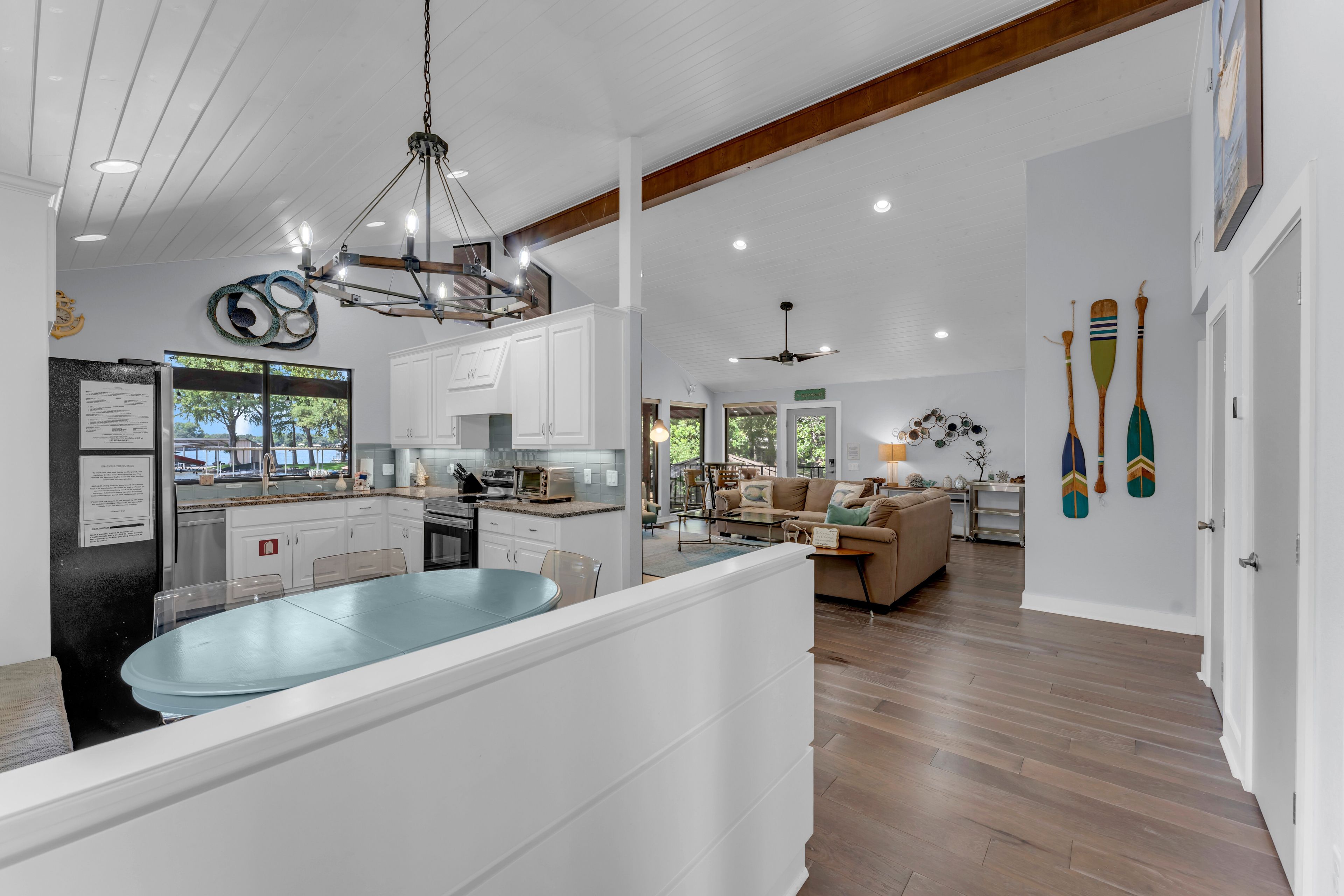 A spacious kitchen with a central island, a dining area with a table, and a living room with a sofa.