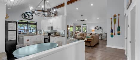 A spacious kitchen with a central island, a dining area with a table, and a living room with a sofa.