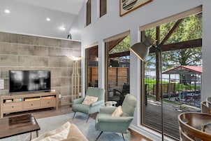 Uma sala de estar moderna com televisão de tela plana, assentos confortáveis e amplas janelas com vista para o exterior.