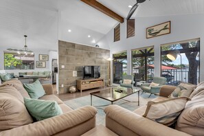 Uma sala de estar ampla com uma televisão grande, assentos confortáveis e vista para o exterior.