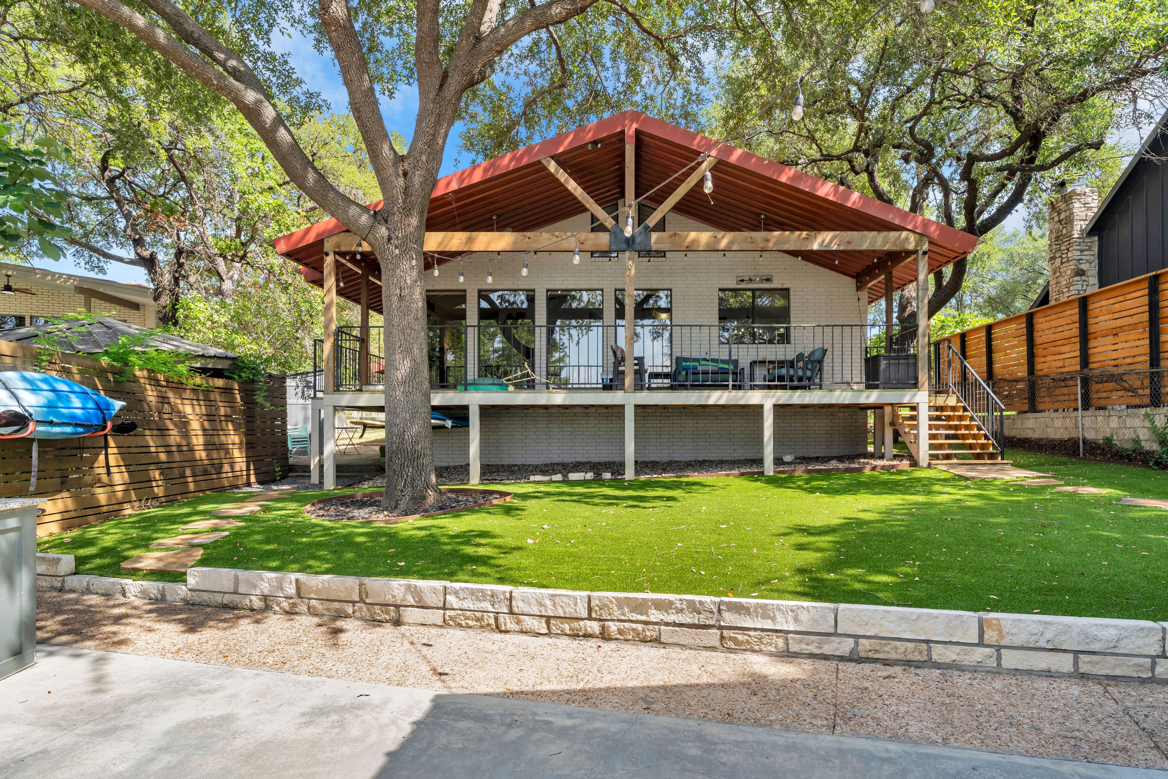 Una casa de dos pisos con un patio cubierto, una escalera de piedra y un patio cercado.