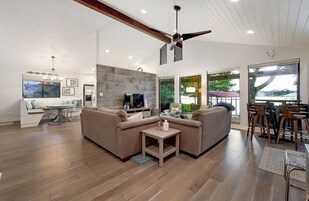 A modern living room with a sectional sofa, a TV, and a dining area with bar stools.