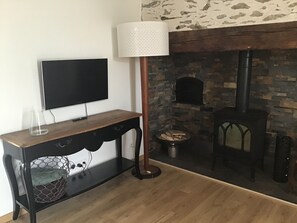 A living room with a television, a lamp, a fireplace, and a stone wall.