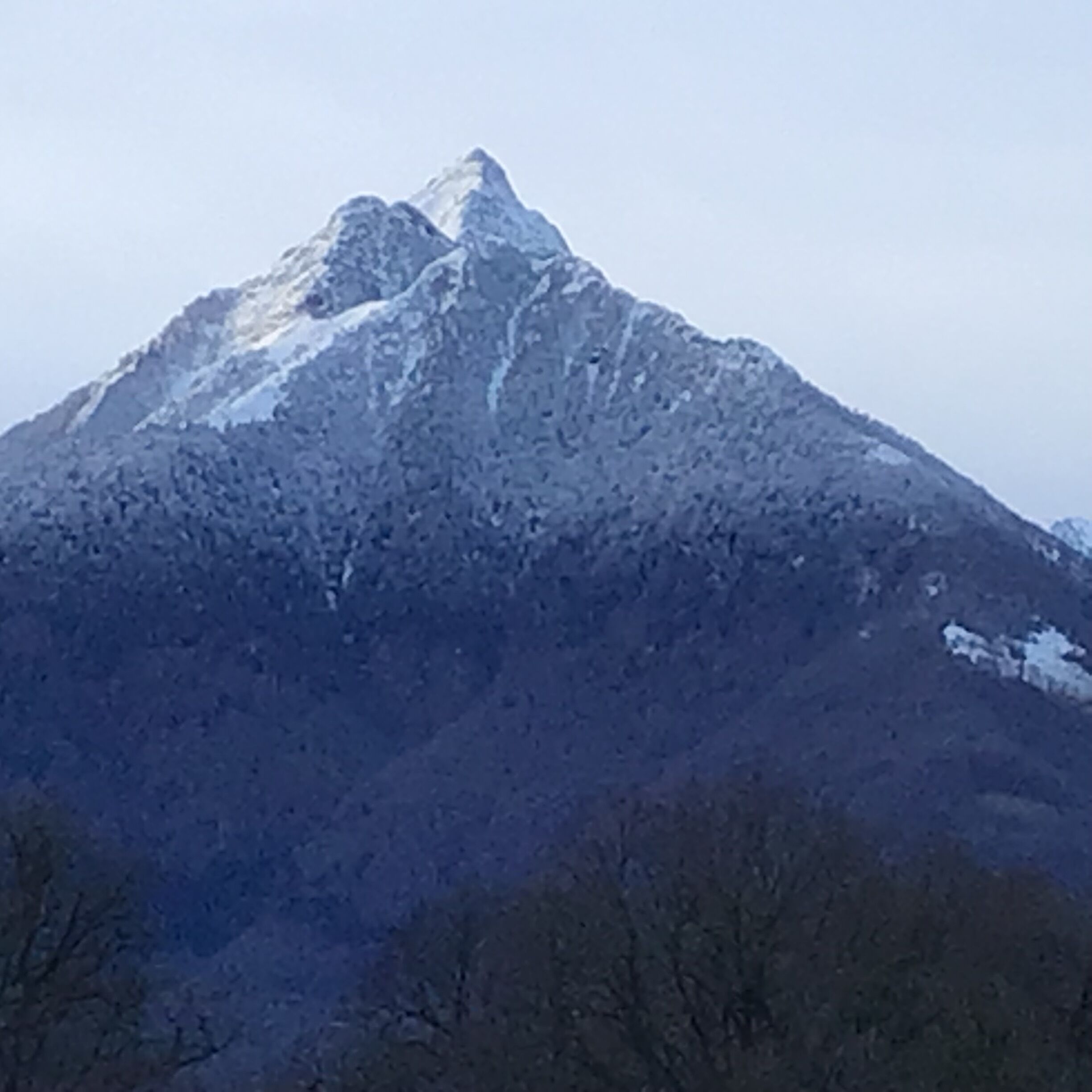 Ein Berg mit schneebedeckter Spitze und blauem Himmel.