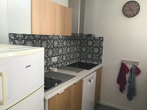 A compact kitchen with a refrigerator, a sink, and a wall-mounted clock. - At the foot of the Hautacam climb (Ayros-Arbouix)