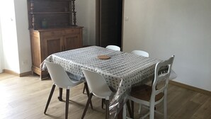 Zona pranzo con tavolo ricoperto da una tovaglia fantasia, circondato da sedie bianche.