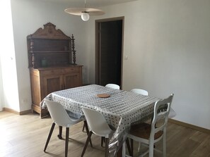A dining area with a table covered by a patterned tablecloth, surrounded by white chairs. - At the foot of the Hautacam climb (Ayros-Arbouix)