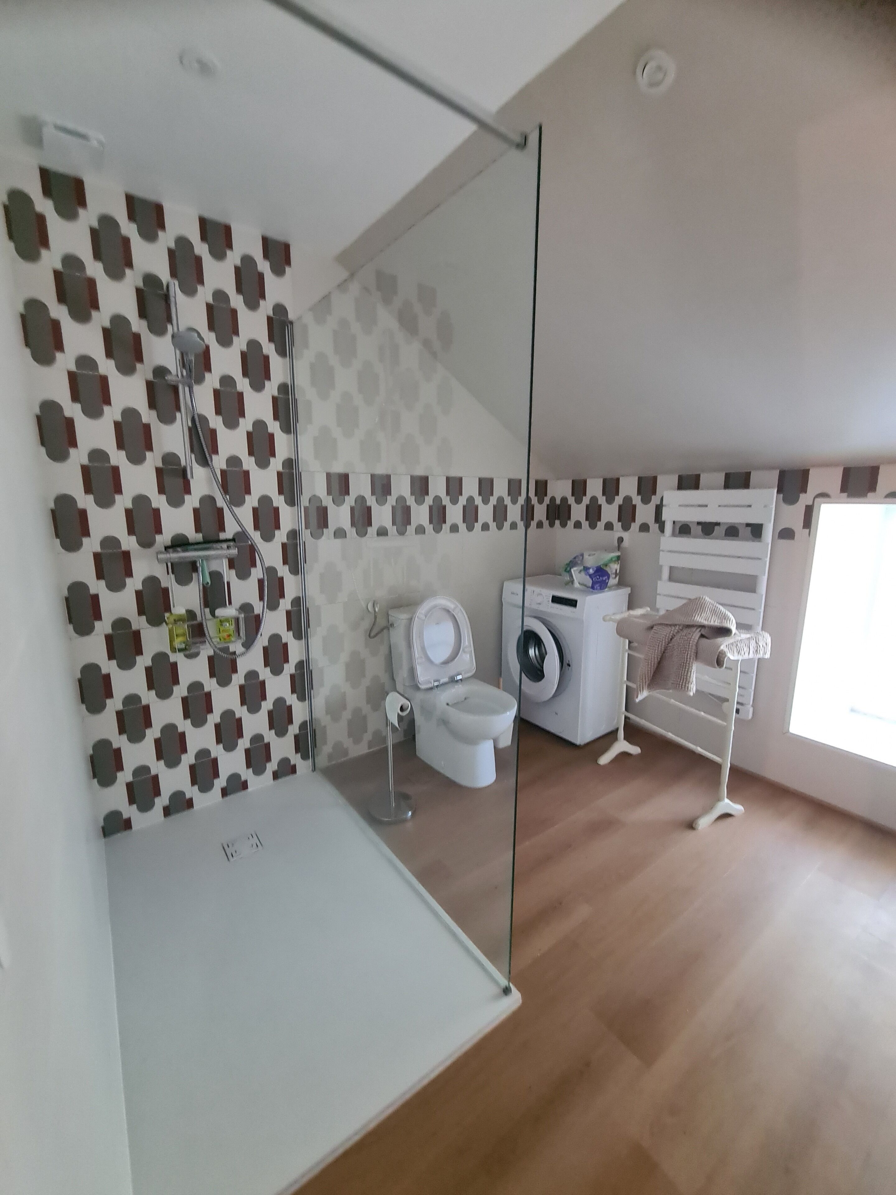 Et moderne badeværelse med brusebad, toilet og vaskemaskine.