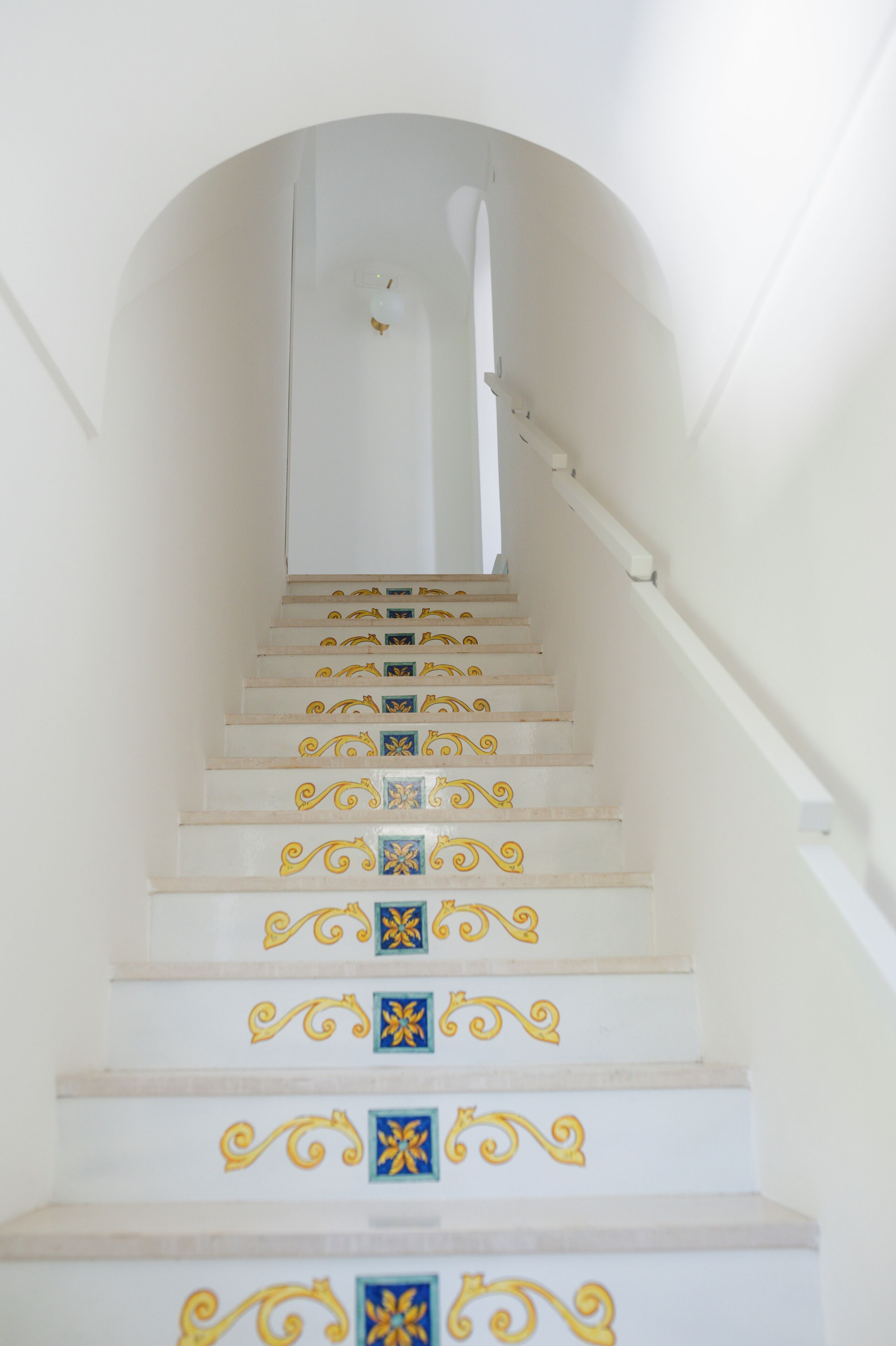 A staircase with white steps and decorative blue and yellow tiles.