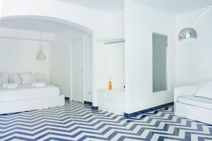 A modern hotel room with a large bed, a bedside table, a wardrobe, and a bathroom with a mirror and window. - Casacasa Positano (Campania)