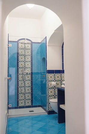 A bathroom with a shower enclosure, a toilet, and a sink. - Casacasa Positano (Campania)