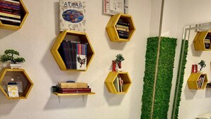 A bedroom with a bed, a green wall decoration, and multiple hexagonal shelves with books and small plants.