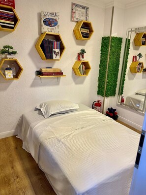 A bedroom with a bed, a green wall decoration, and multiple hexagonal shelves with books and small plants. - Studio 40 square metres, 2.2 km to the centre, 3.7 km to Palace of Parliament (București)