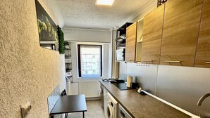 A compact kitchen with a built-in washer, a small dining table, and a window providing natural light.