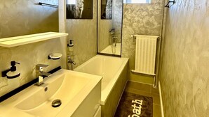 A modern bathroom with a double sink, a large mirror, a shower, and a towel rack.