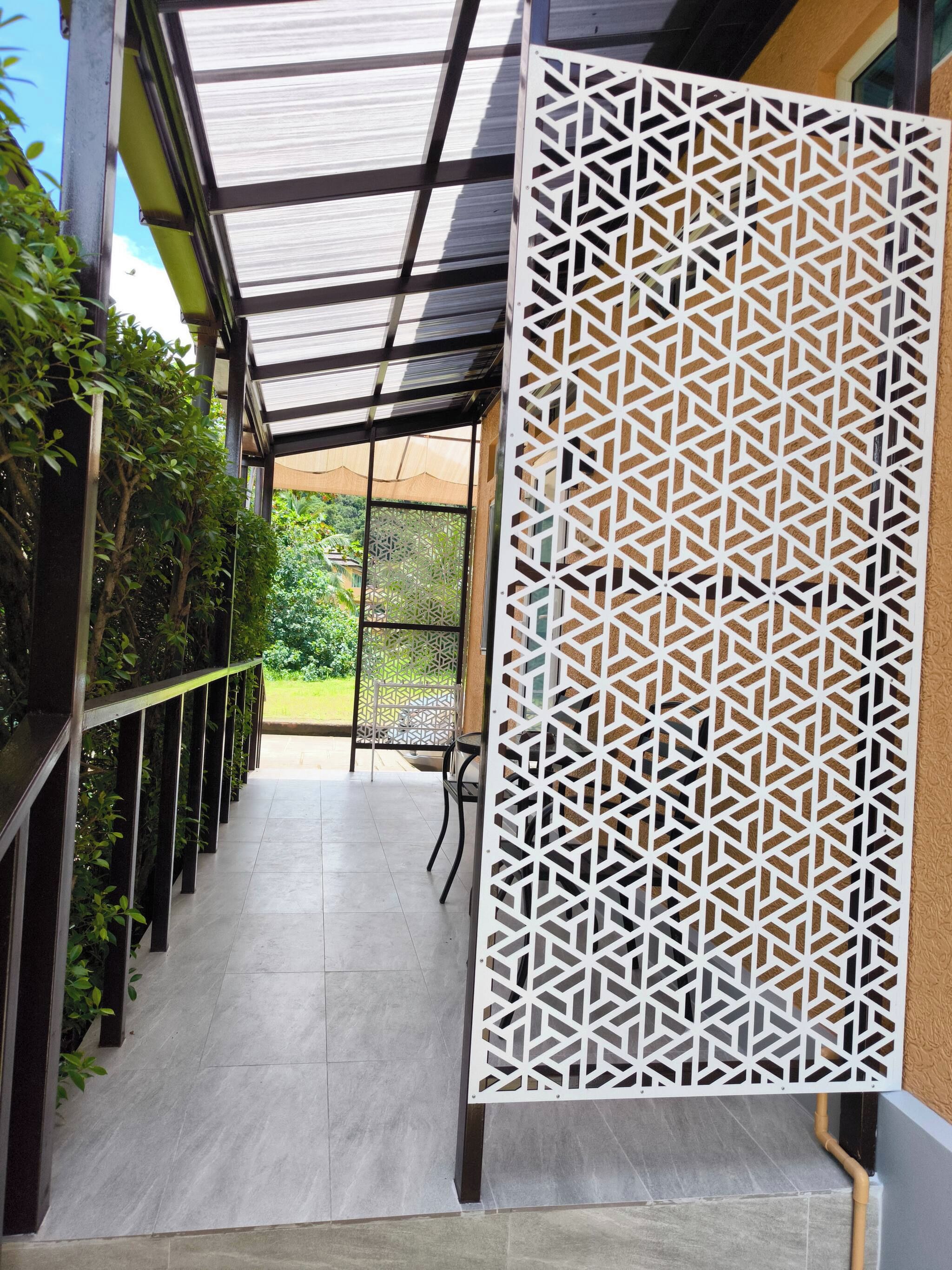 A corridor with a patterned screen, a tiled floor, and a view of greenery outside.