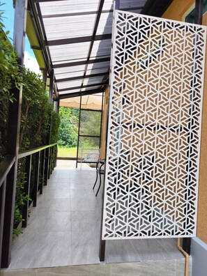 A corridor with a patterned screen, a tiled floor, and a view of greenery outside. - Room-villa 21D - Golf Room (Ko Chang)