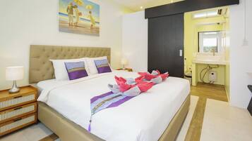 A hotel room with a large bed, a headboard, a painting, a nightstand, a lamp, a bathroom with a sink and mirror.