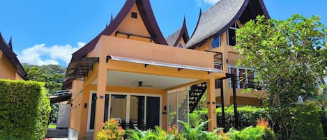 A traditional building with a covered entrance, potted plants, and a clear sky.