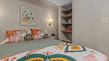 Ein Schlafzimmer mit einem Bett, Kissen, einer Wandleuchte und einem gerahmten Bild.