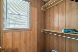 A wooden interior with a window, a metal shelf, and a metal rod. - Easy Access to US-54 | Fenced Yard + W/D | Perfect for Travel Nurses! (Wichita)