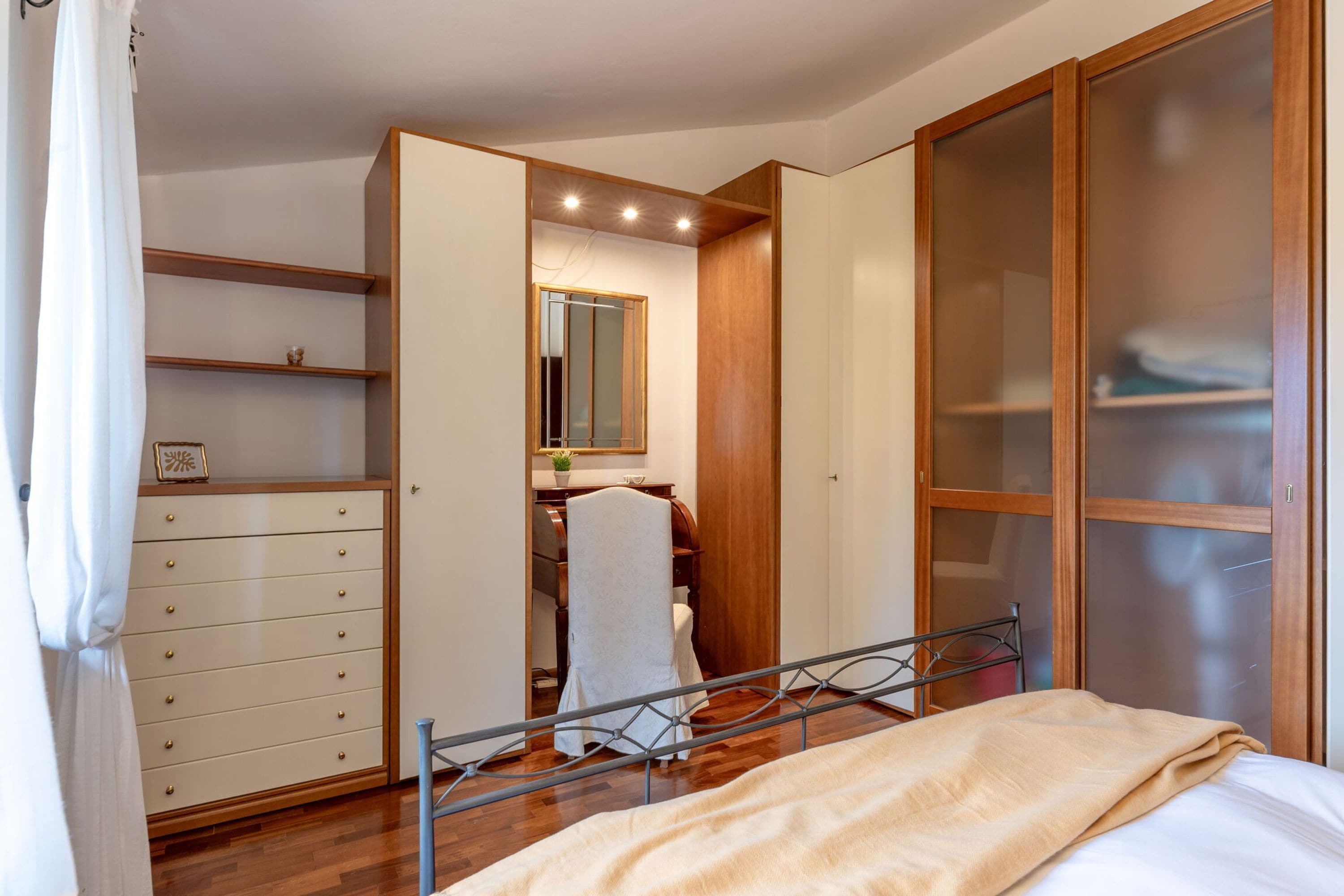 A bedroom with a bed, a wardrobe, a dresser, and a mirror.