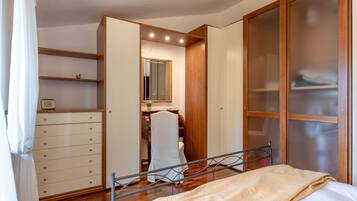 A bedroom with a bed, a wardrobe, a dresser, and a mirror.
