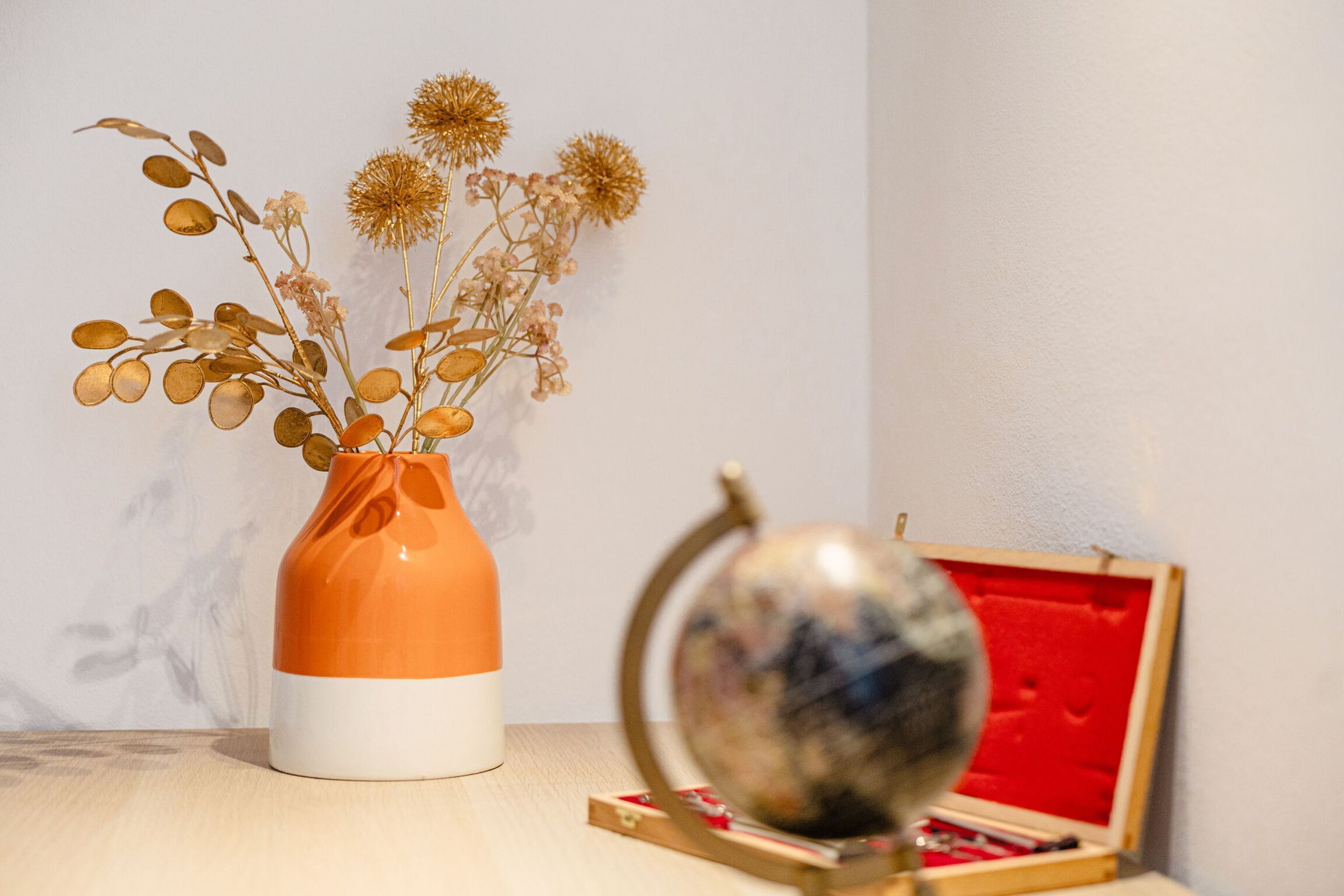 A vase with dried flowers and a globe on a table.