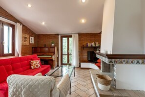 A living room with a red sofa, a glass coffee table, a fireplace, and a television. - Casa Miramonti in Perugia (Perugia)