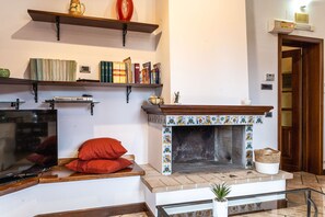 A living room with a fireplace, bookshelves, a television, and a red pillow on a bench. - Casa Miramonti in Perugia (Perugia)